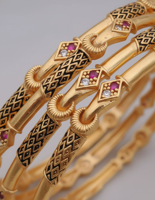 Gold bracelets with intricate designs and gemstones on a gray background