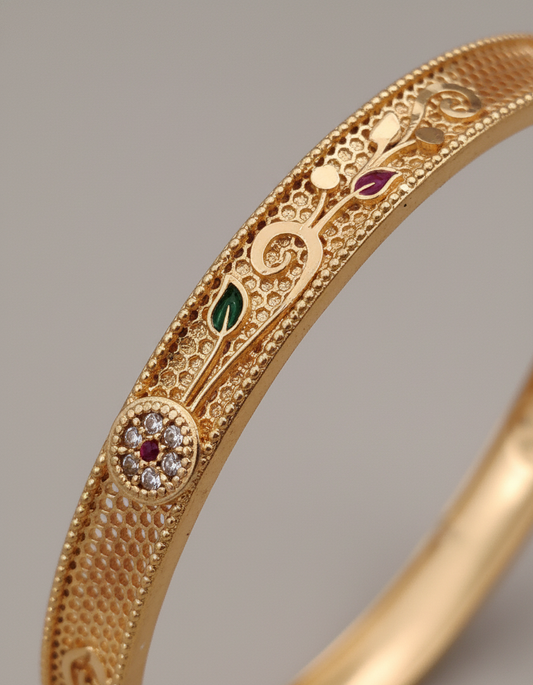 Gold bracelet with intricate designs and gemstones on a gray background