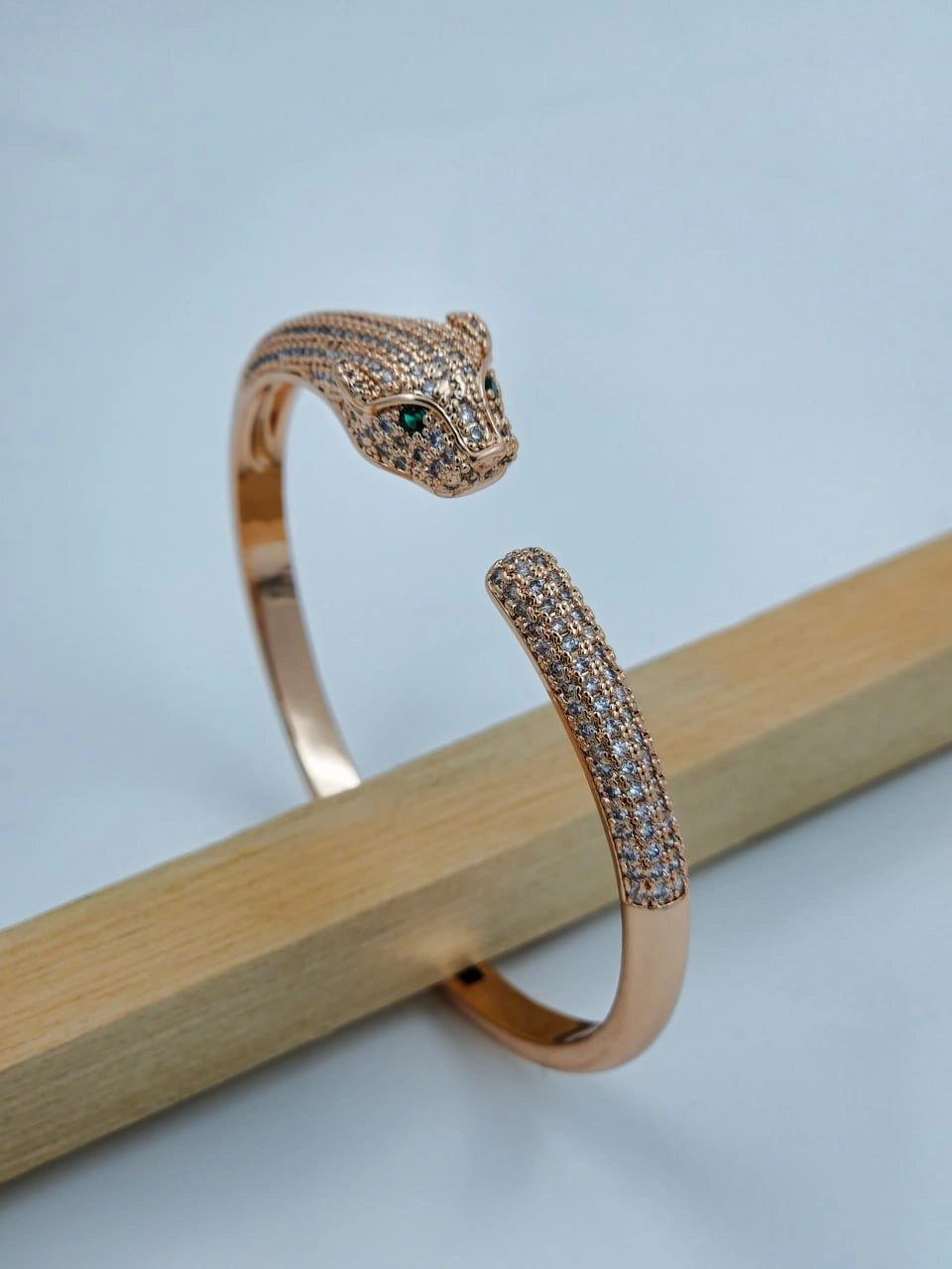 Rose gold bracelet with panther design on a light gray background