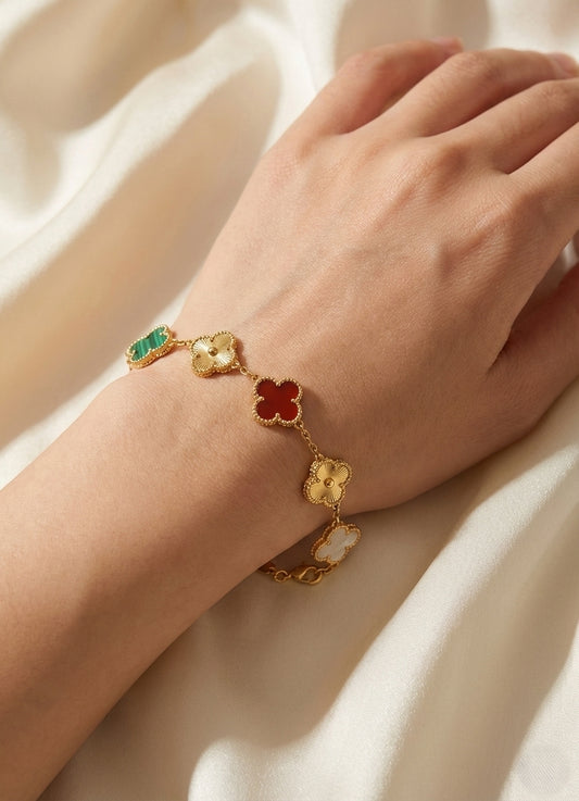 Gold bracelet with floral charms on a wrist against a soft background