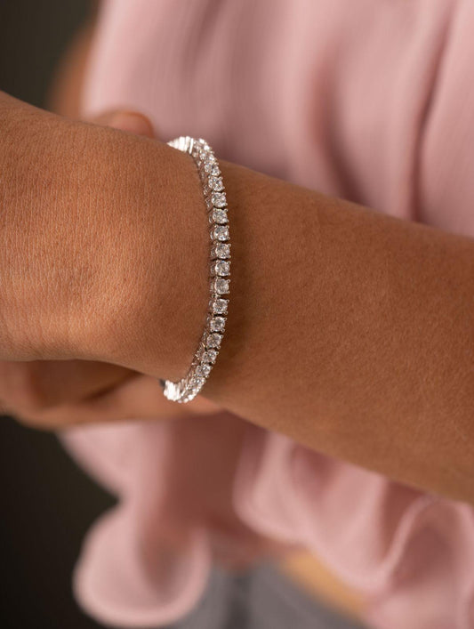 Silver bracelet on a wrist with a blurred pink garment in the background