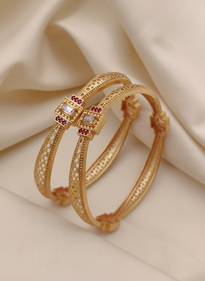 Gold bangles with gemstones on a beige fabric background