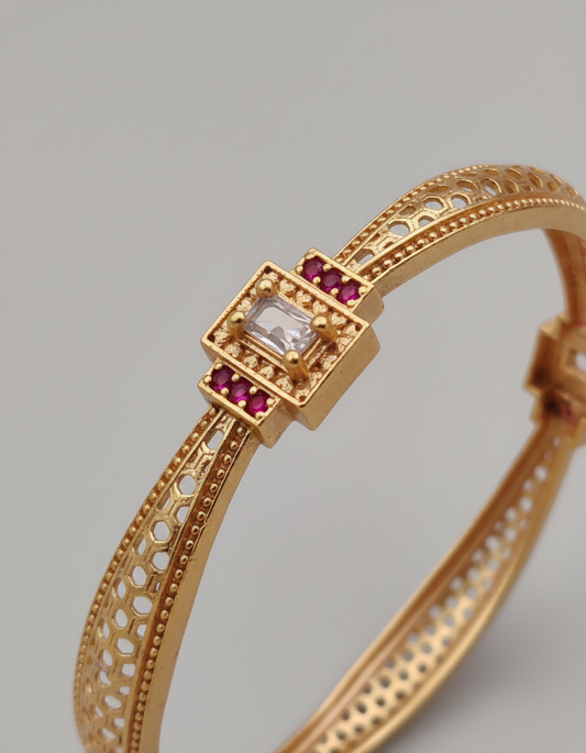 Gold bracelet with gemstones on a gray background