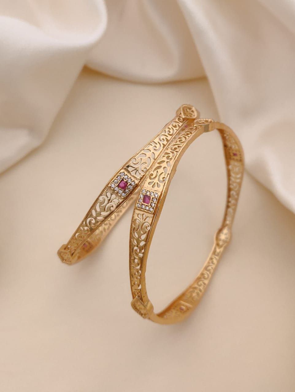 Gold bracelet with red gemstones on a beige fabric background