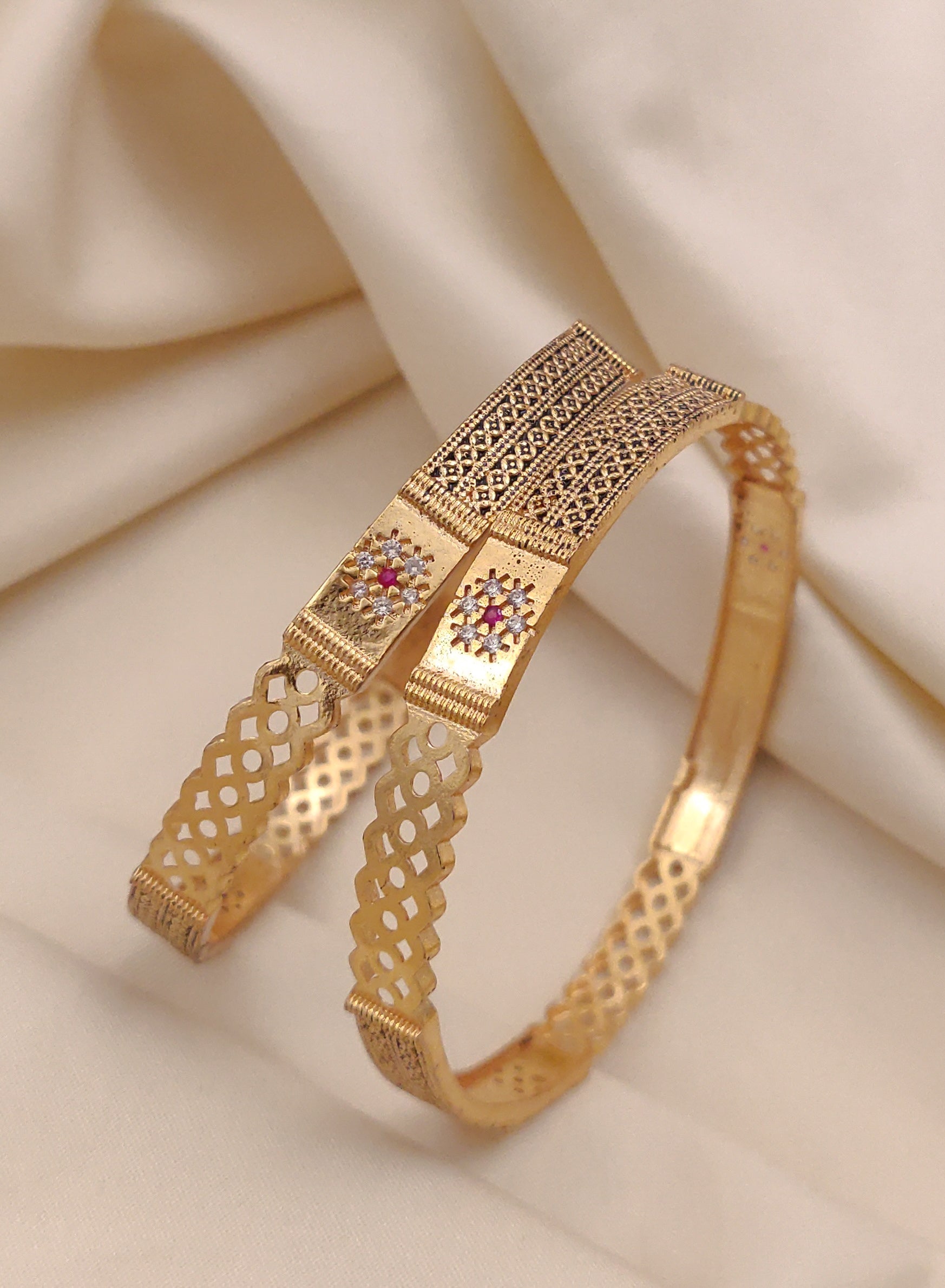 Gold bracelet with intricate design on a beige fabric background