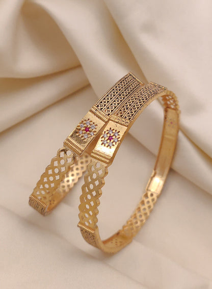 Gold bracelet with intricate design on a beige fabric background