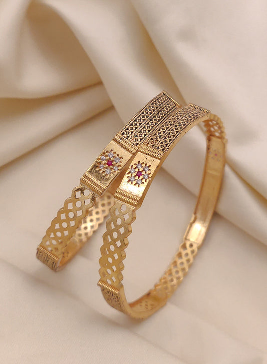 Gold bracelet with intricate design on a beige fabric background