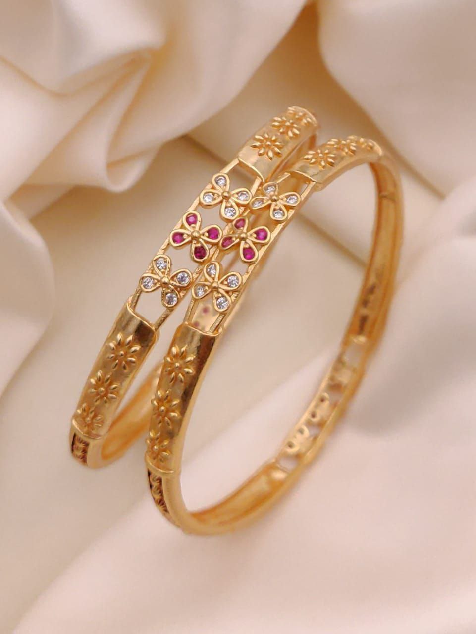 Gold bracelet with floral design and gemstones on a soft beige background