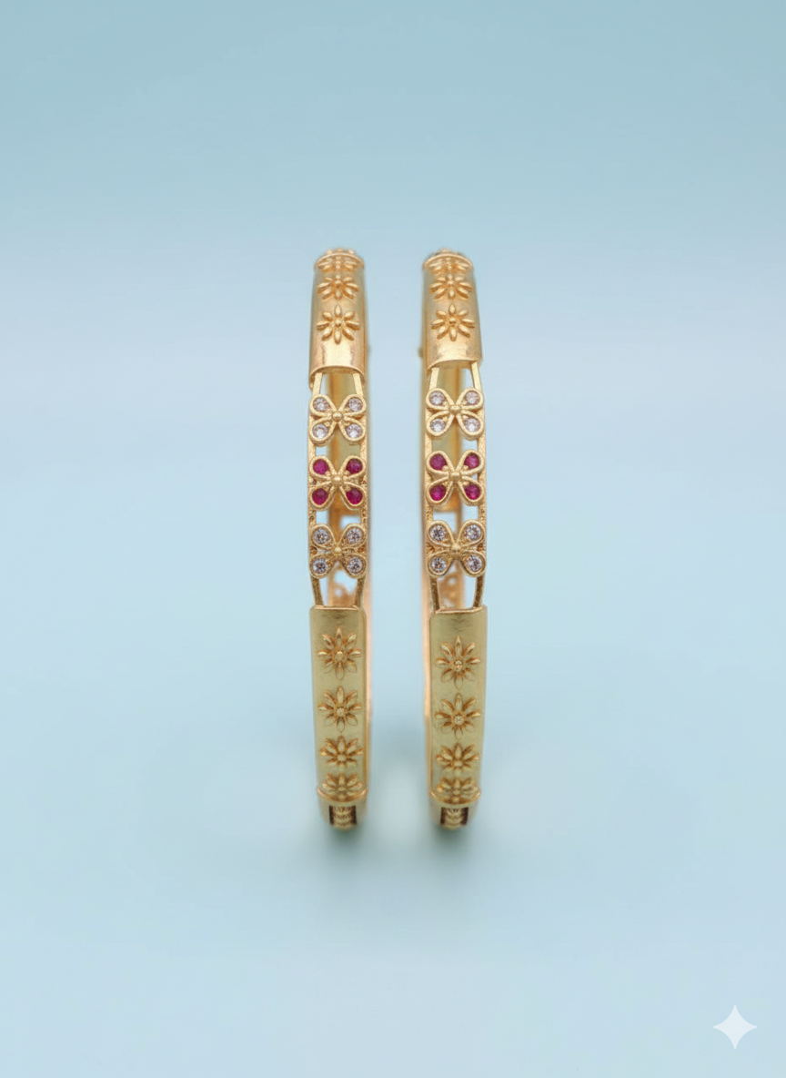 Gold bangles with red gemstones on a light blue background