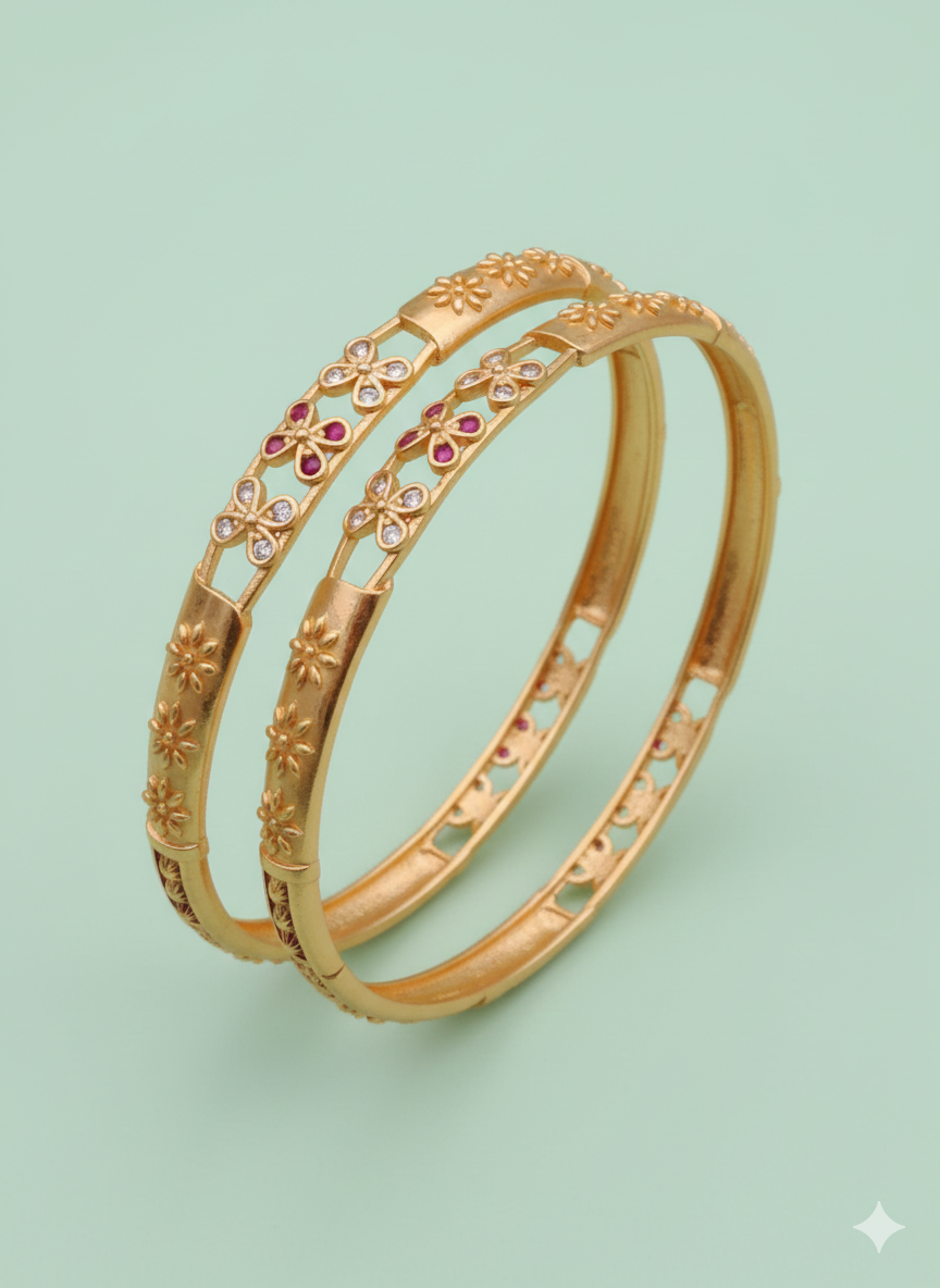 Two gold bangles with floral designs on a light green background