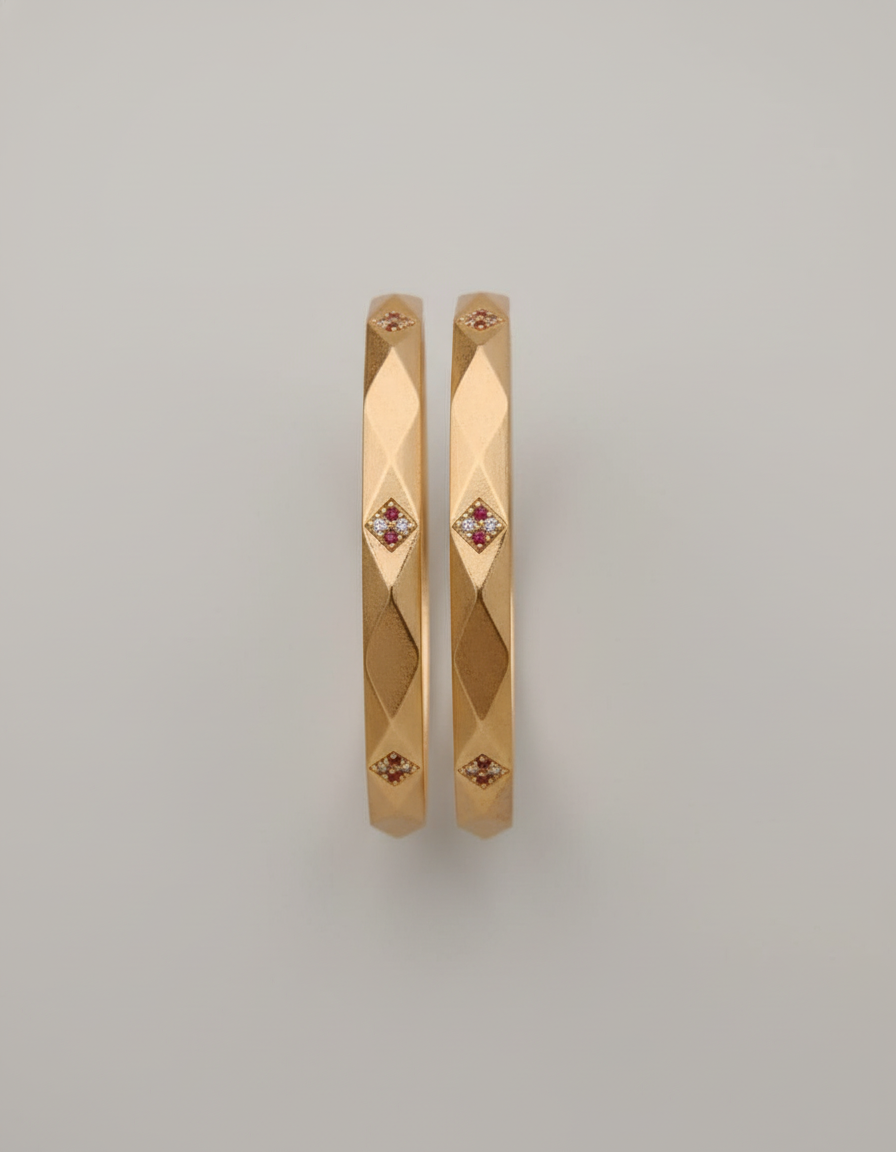 Gold bangles with embedded stones on a light gray background