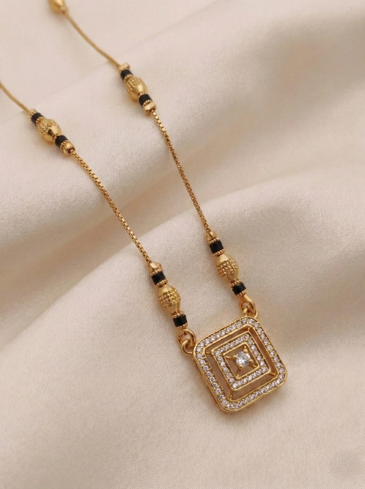 Gold mangalsutra with a square pendant on a beige fabric background