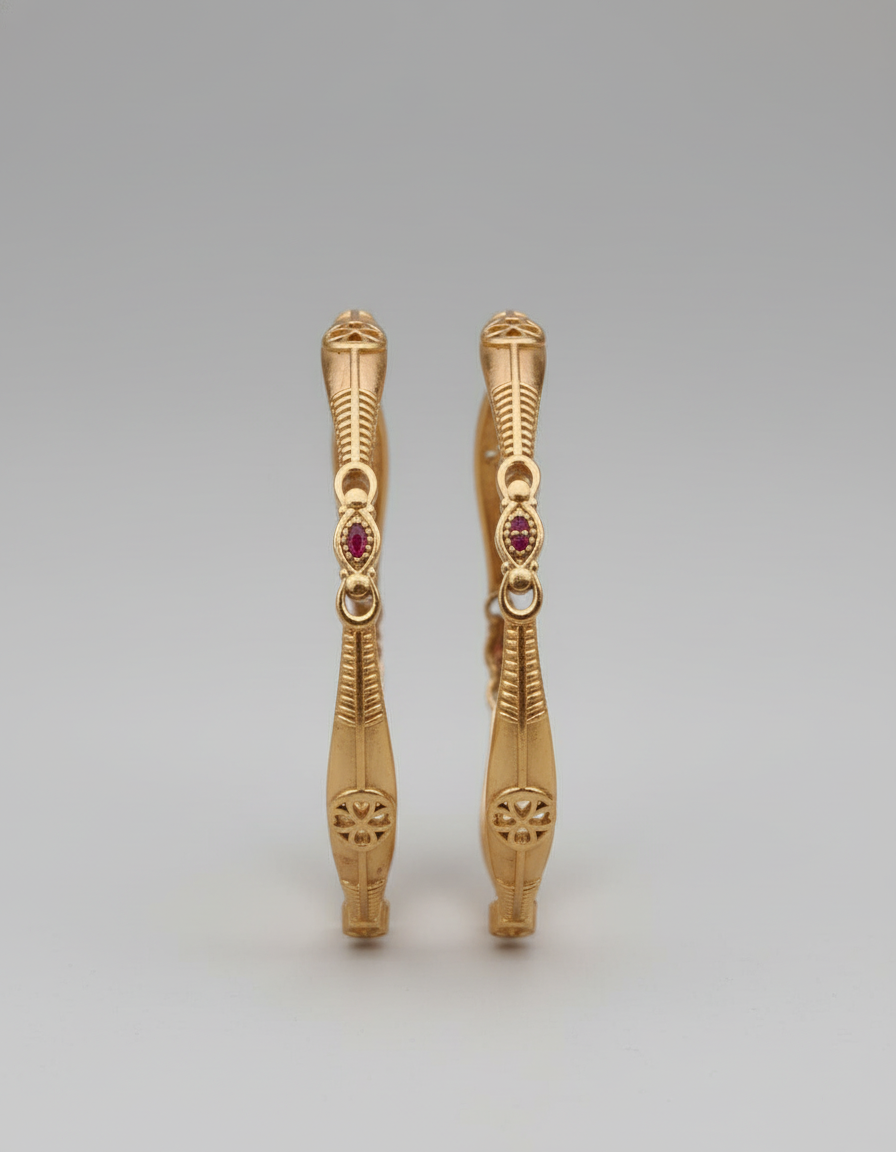Pair of gold earrings with red gemstones on a gray background