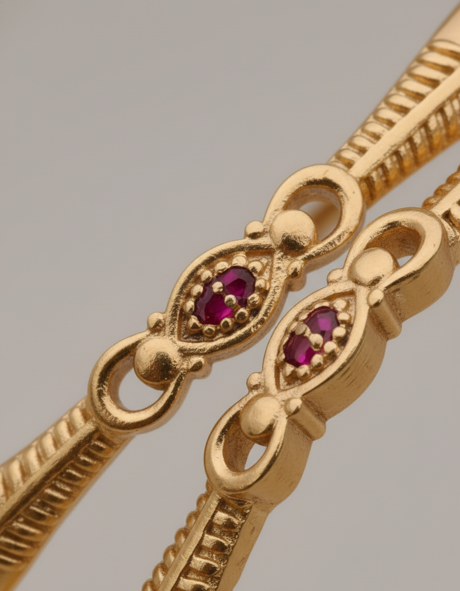 Gold bracelet with red gemstones on a gray background