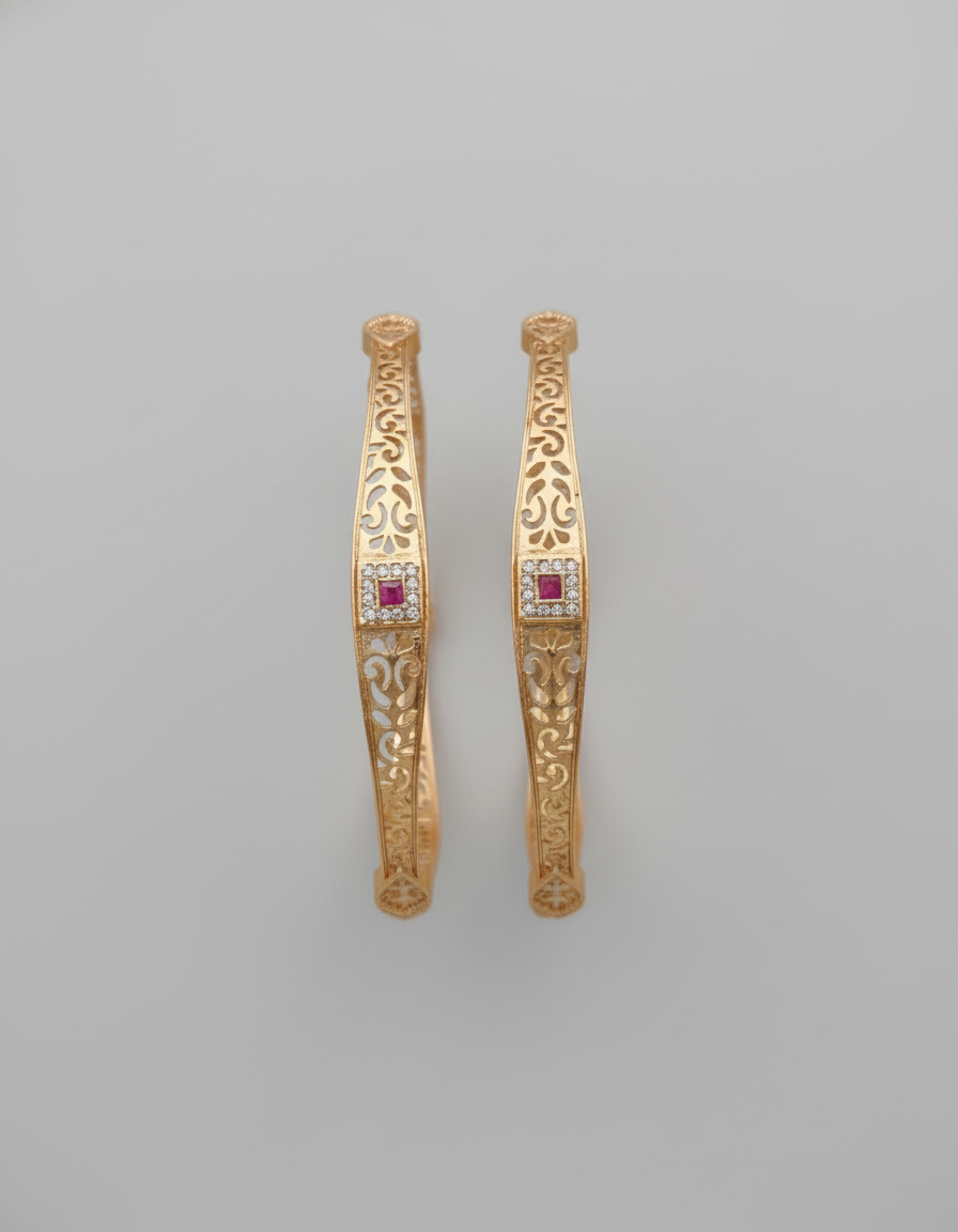 Pair of gold earrings with red gemstones on a gray background