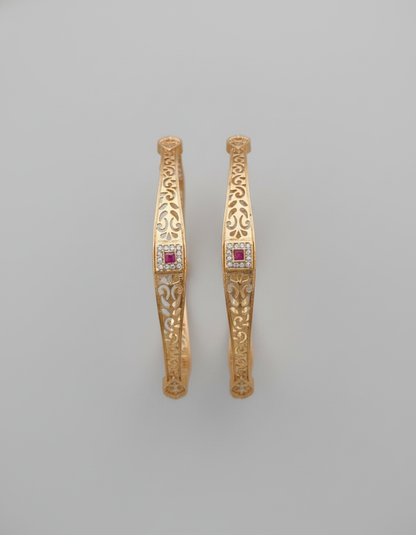 Pair of gold earrings with red gemstones on a gray background