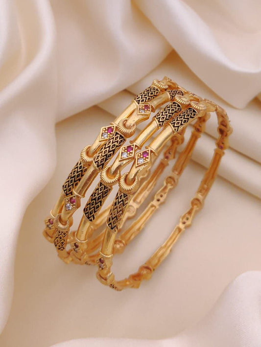Set of gold bangles with intricate designs on a soft beige background