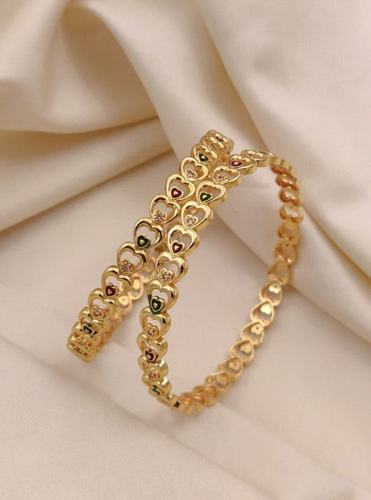 Gold bracelet with heart designs on a beige fabric background