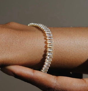 Close-up of a hand wearing a diamond bracelet on a neutral background