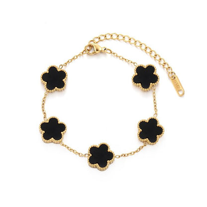 Gold bracelet with black clover-shaped charms on a white background
