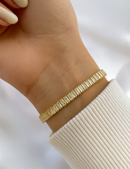 Gold bracelet on a wrist with a white background