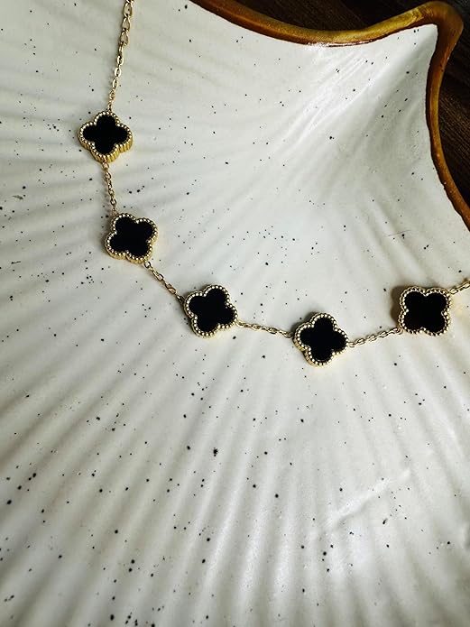 bracelet with black clover-shaped charms on a white textured surface