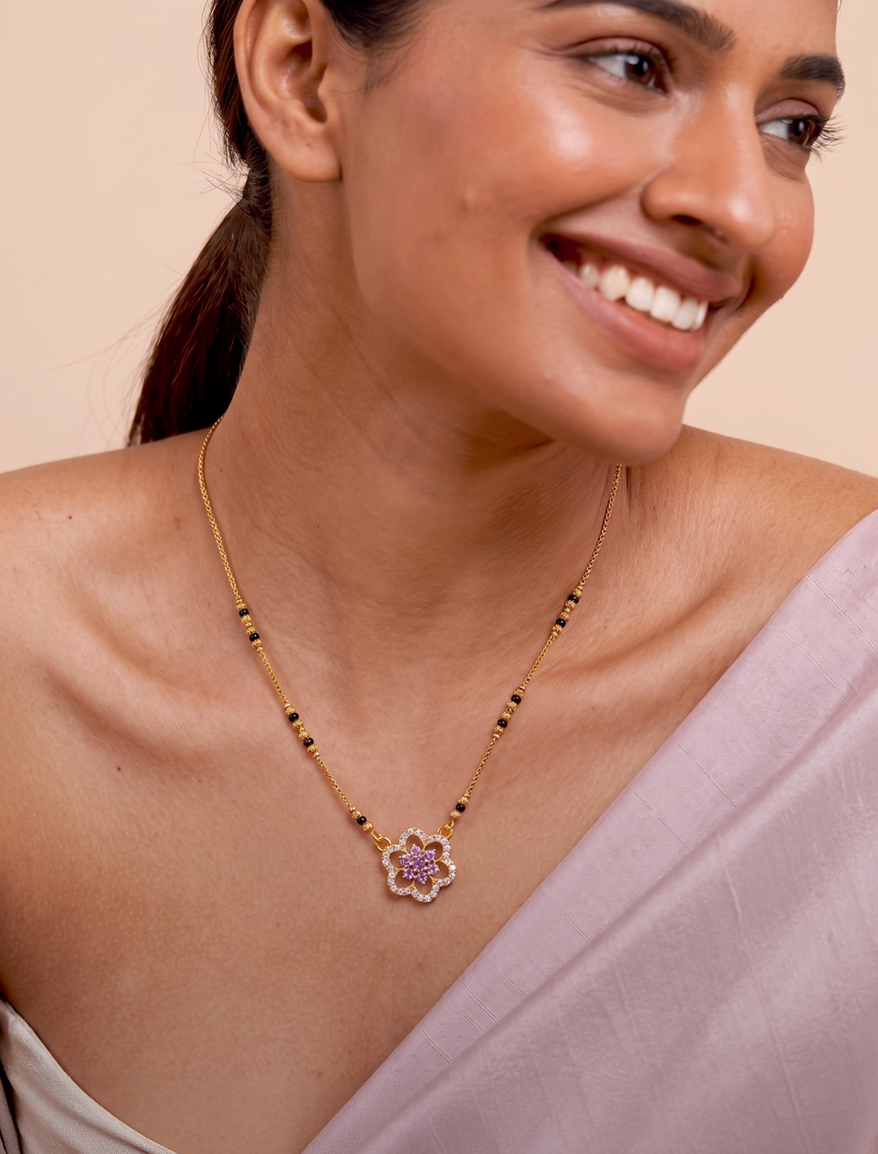 Woman wearing a gold mangalsutra with a purple pendant on a beige background