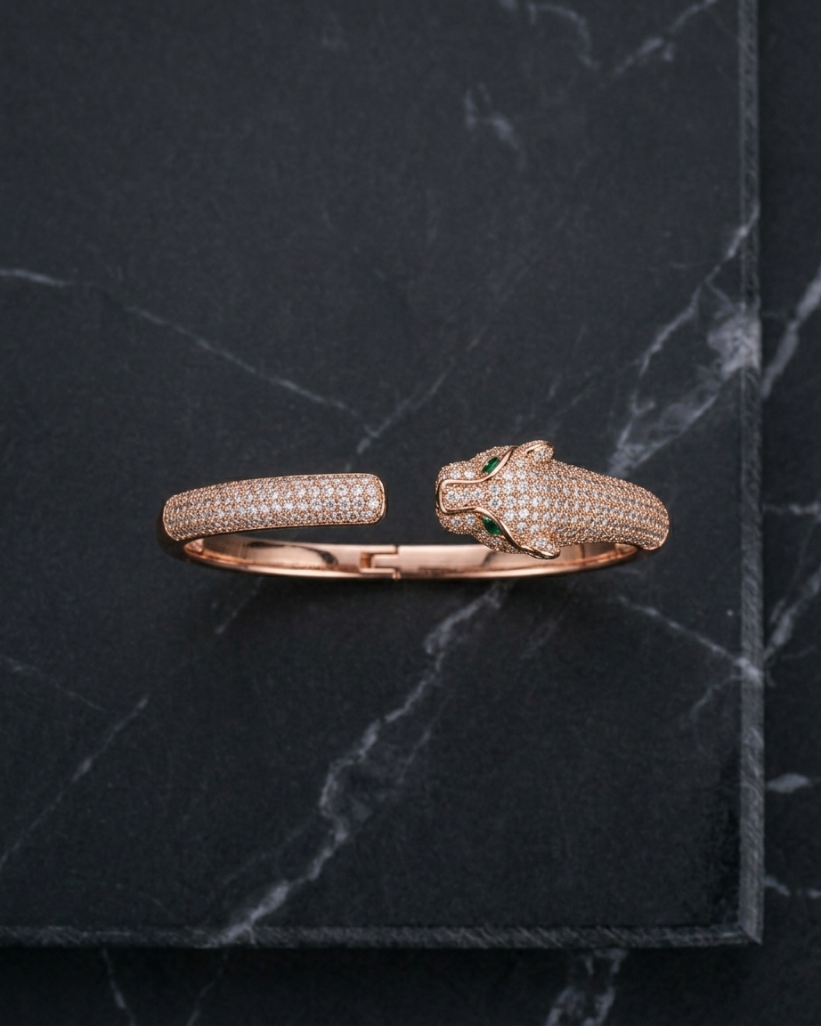 Rose gold panther-shaped bracelet with embedded stones on a dark marble surface