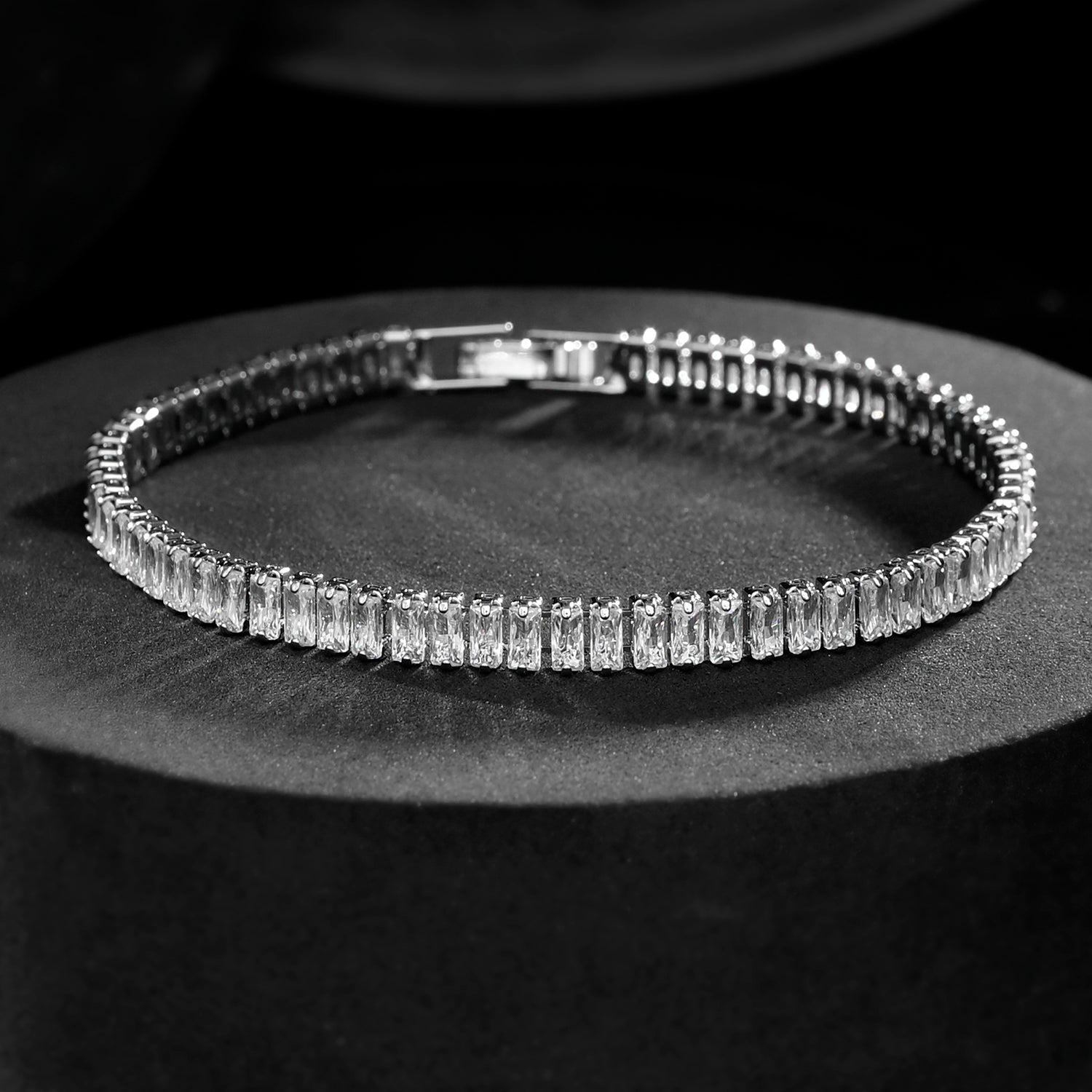 Silver bracelet with clear stones on a dark surface