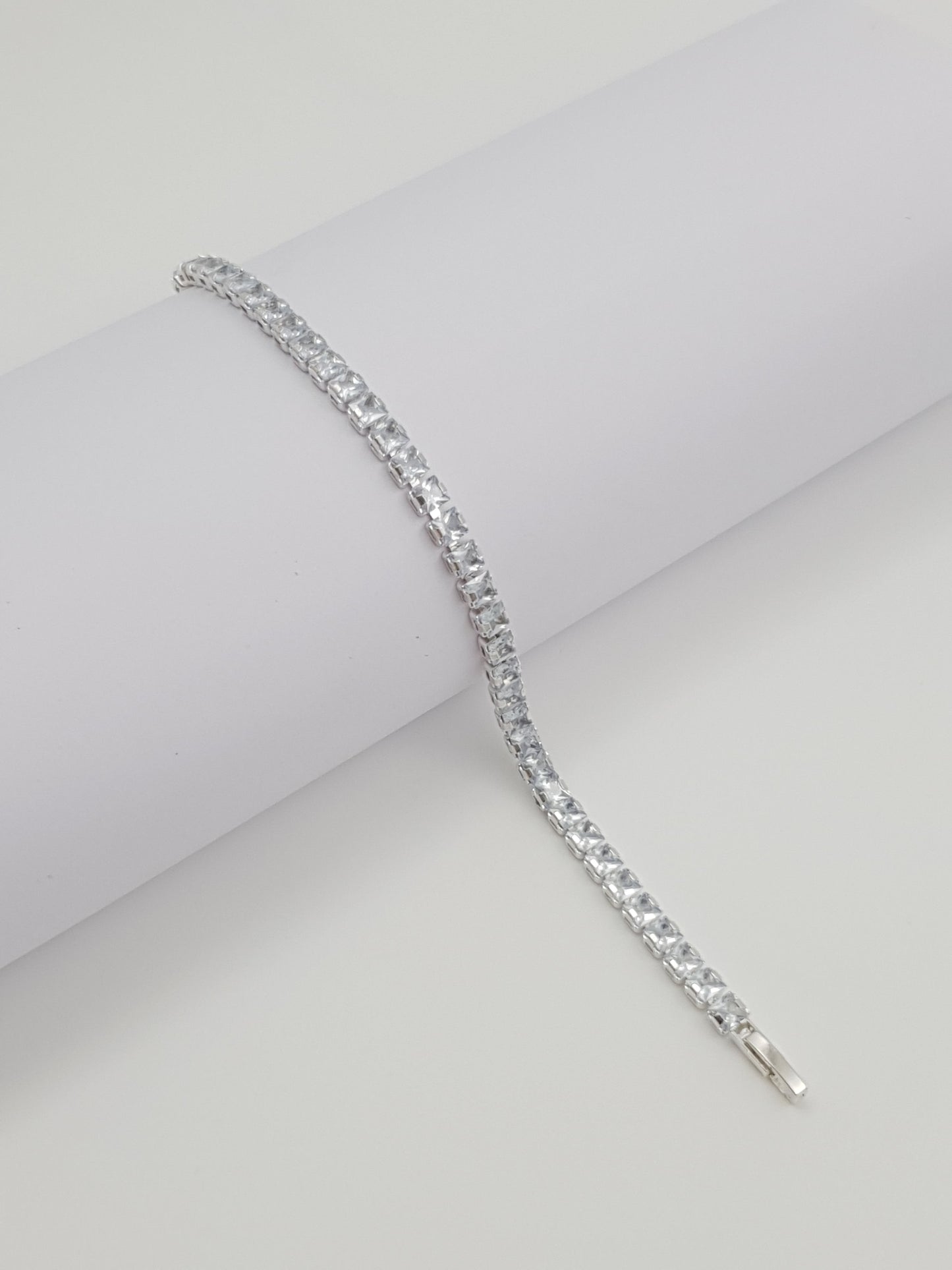 Silver bracelet with clear stones on a light gray background