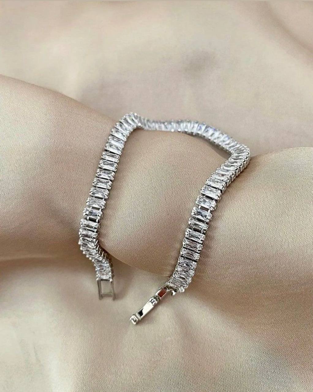Silver bracelet with clear stones on a wrist against a neutral background