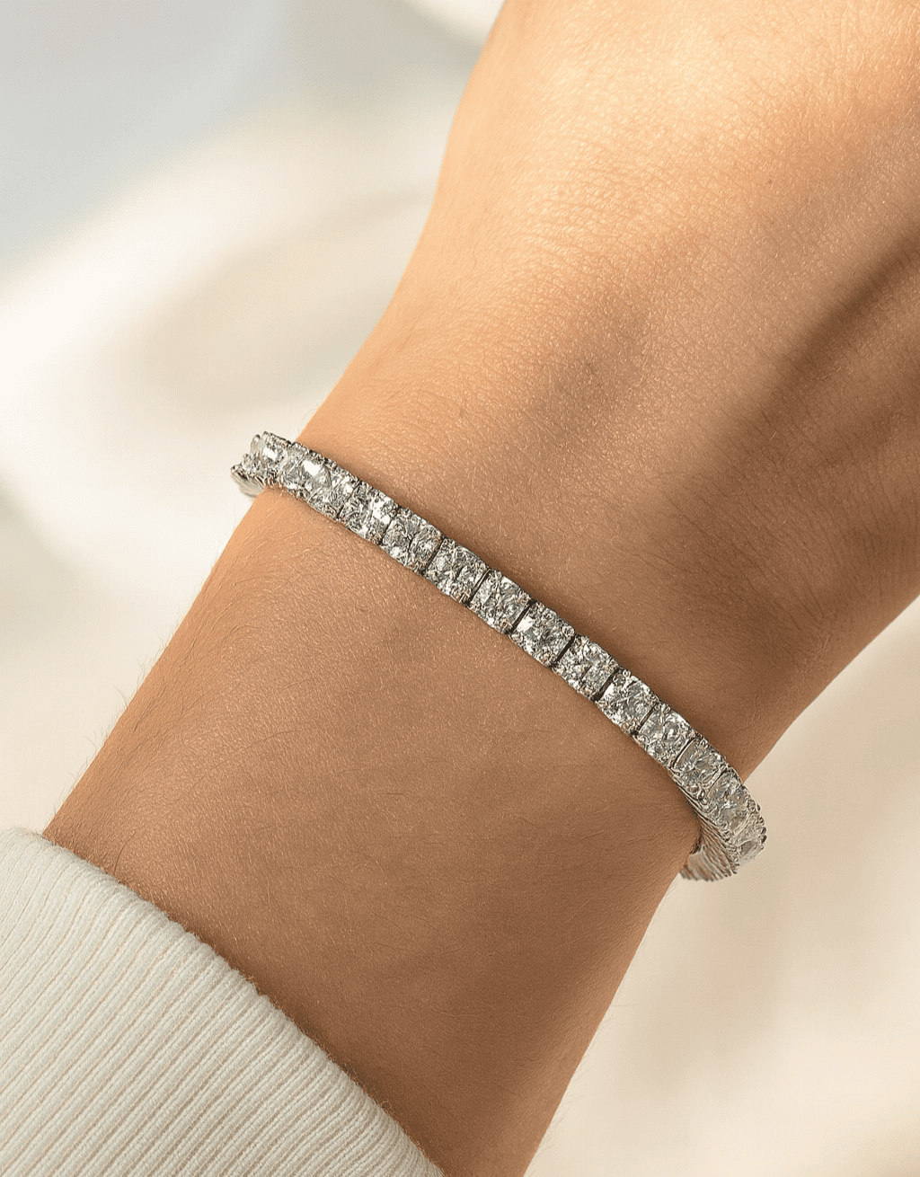Silver bracelet with clear stones on a wrist against a neutral background