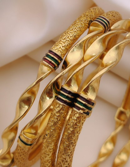 Gold bangles with intricate designs on a light background